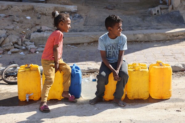 팔레스타인 가자시티에 급수난이 심각한 가운데  두 아이가 물통 위에 앉아 어딘가를 바라보고 있다. 2024. 06. 10 [AFP=연합뉴스]