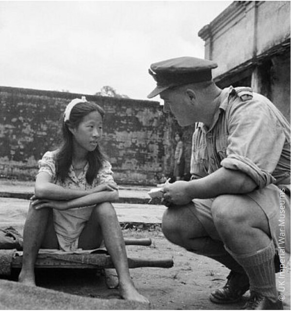 일본군 ‘위안부’에 소속된 중국인 소녀가 미얀마 랑군(양곤)의 한 캠프에서 들것에 앉아 심문을 기다리고 있다. (1945년 8월 8일)     앰네스티 인터내셔널