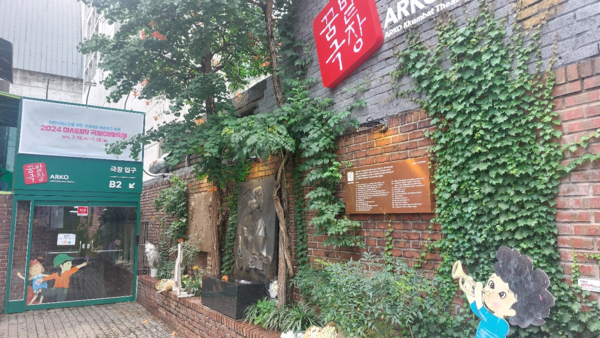 ‘꿈밭극장’으로 변한 학전소극장. 김민기가 걸터앉곤 하던 극장 입구 축대 위 담벼락에는 그가 심은 나무와 능소화가 싱그러운데, 그도, 콘서트 1000회 기념 부조로 남은 김광석도 가고 없다. © 이봉수