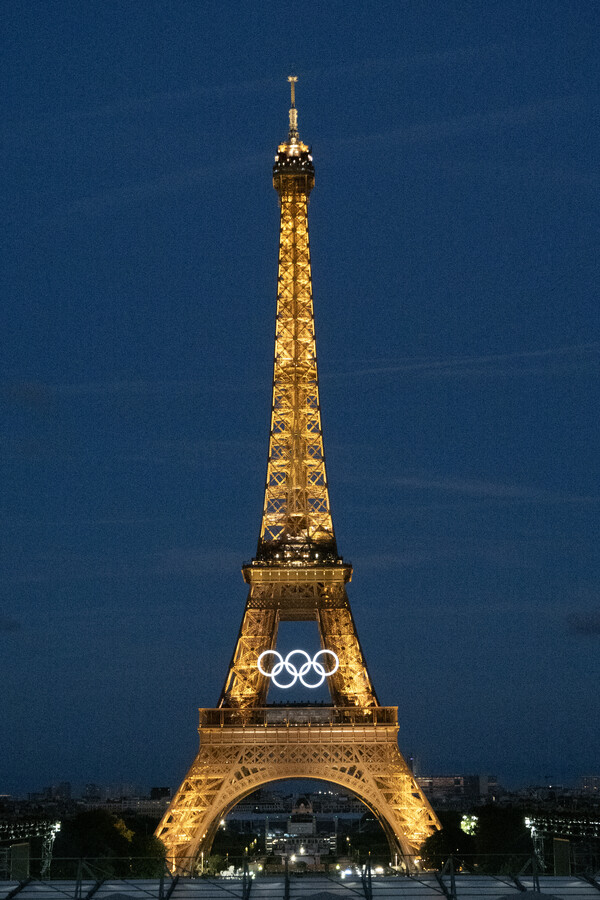 2024 파리올림픽 개막을 5일 앞둔 21일(현지시간) 파리의 상징 에펠탑에 대형 오륜 조형물이 점화됐다. 파리올림픽 조직위원회 측은 재활용 강철로 만든 링 5개를 지상에서 조립한 뒤 두 대의 대형 크레인으로 에펠탑 1층과 2층 사이, 지상 70ｍ 높이에 설치했다고 밝혔다. 오륜 조형물은 폭 29ｍ, 높이 13ｍ에 무게는 30t에 달한다. 2024.07.22. UPI 연합뉴스