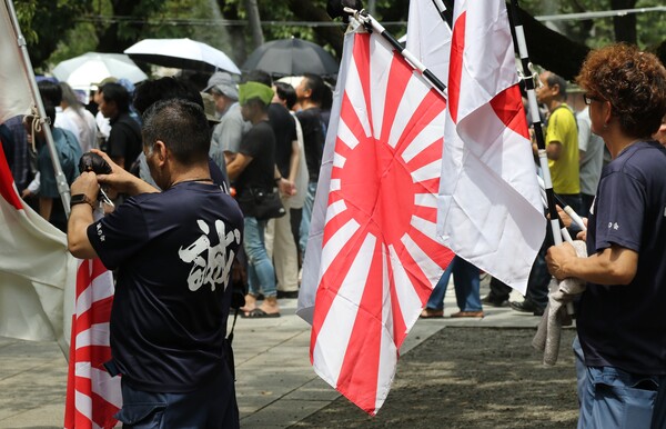 일본 패전일인 15일 태평양전쟁 A급 전범이 합사된 도쿄 지요다구 야스쿠니신사에서 남색 제복을 입은 사람들이 욱일기와 일장기를 들고 있다. 2024.8.15. 연합뉴스