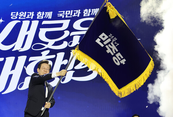 더불어민주당 당대표 연임에 성공한 이재명 신임 당대표가 18일 오후 서울 송파구 올림픽공원 KSPO돔에서 열린 전국당원대회에서 박찬대 대표 직무대행 겸 원내대표로부터 전달받은 당기를 흔들고 있다. 2024.8.18 [공동취재] 연합뉴스