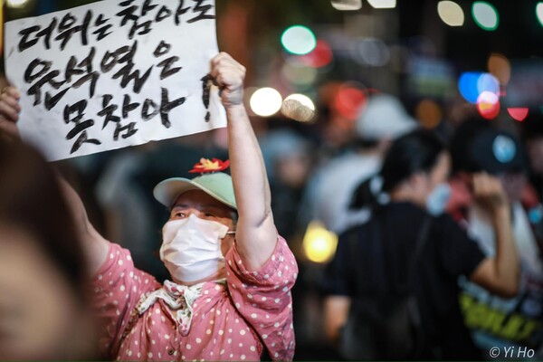 104차 촛불대행진 집회에서 한 찬석자가 '더위는 참아도 윤석열은 못참아'라고 쓰인 종이피켓을 높이 들고 있다. 이호 작가 사진