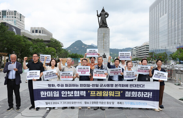 31일 오전 서울 광화문 이순신 동상 앞에서 자주통일평화연대 관계자들이 손팻말을 들고 한미일 안보협력 프레임워크 철회를 촉구하고 있다. 2024. 07.31 연합뉴스