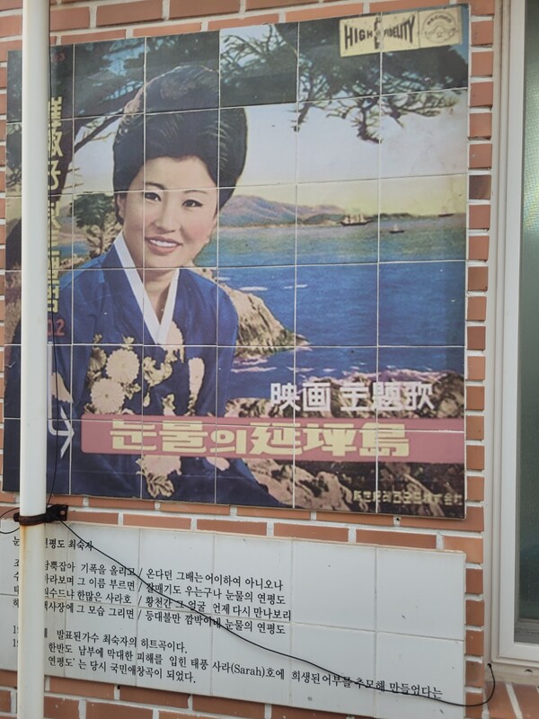 ​1964년 발표된 가요 '눈물의 연평도' 노래가사 및 영화 포스터. '조기까시 역사문화탐방로' 골목길 집 벽면에 전시된 사진의 하나다. 연평도는 사라호 태풍 전까지만 해도 전국에서 조기잡이 배들이 몰려들어 파시를 이뤘다. 지금은 최전선에 위치했지만, 수백년 동안 풍어의 고장이었다. 2024.9.4. 시민언론 민들레 