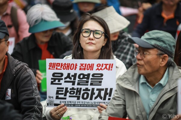 19일 서울 중구 시청역 앞에서 열린 111차 촛불대행진 집회에 참석한 한 시민이 '웬만해야 집에 있지! 윤석열을 탄핵하자!'고 적힌 손팻말을 들고 있다. 2024.10.19. 이호 작가