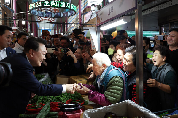 윤석열 대통령이 22일 부산역 인근 초량시장을 찾아 상인에게 인사를 건네며 손을 잡고 있다. 북한군 러시아 파병이 "한반도와 세계평화에 중대 위협"이라면서 이를 논의한 국가안보회의(NSC)  상임위원회에 참석하지 않고 선택한 일정이다. 2024.10.22. [대통령실 제공] 연합뉴스 