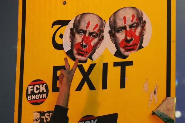 5일 시위대가 이스라엘 수도 텔아비브의 한 도로를 봉쇄한 채 출구 표시에 네타냐후의 얼굴 스티커를 붙인 뒤 한 시민이 승리의 'V'자를 보여주고 있다. 2024. 11. 05 [AFP=연합뉴스]