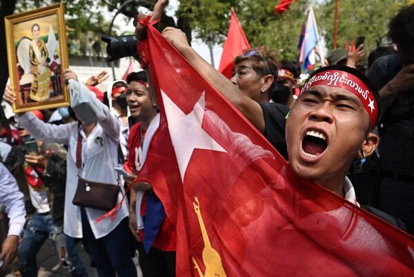 미얀마 군부 쿠데타 3주년인 1일(현지시간) 태국 방콕의 유엔사무소 밖에서 미얀마 국기를 몸에 두른 시위대가 군정 종식을 촉구하는 구호를 외치고 있다. 옆에는 아웅 산 수치 사진을 든 이도 보인다. 2024.02.01. AFP 연합뉴스