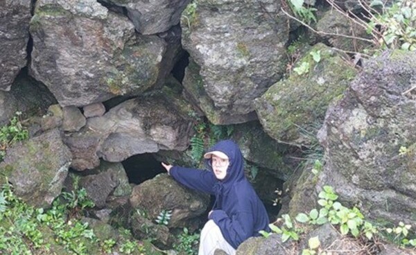 손가락으로 가리키고 있는 다랑쉬굴 입구는 사람이 겨우 기어들어갈 만큼 좁지만 안은 꽤 넓다. © 이봉수  