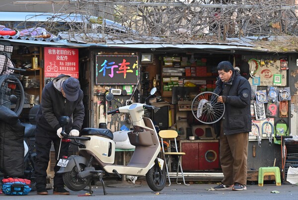 11월 29일 베이징의 전통적인 안뜰 주택이 있는 좁은 골목길인 후퉁의 작업장에서 일하고 있는 사람들. 2024.11.29. AFP 연합뉴스