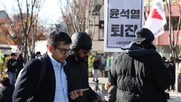 윤석열 대통령이 긴급 대국민 담화를 통해 비상계엄 해제를 선언한 4일 오전 서울 종로구 광화문광장에서 한 외국인 관광객이 계엄 반대 집회를 지나치고 있다. 2024.12.4. 연합뉴스