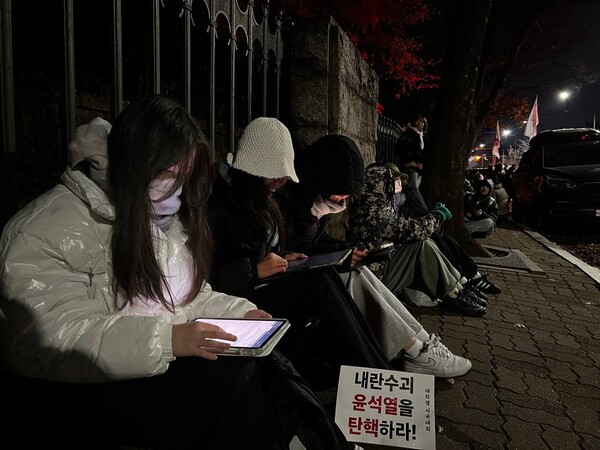 시험을 앞 둔 학생들이 국회 담장 아래서 시험공부를 하고 있다. 2024.12.07. 민주노총