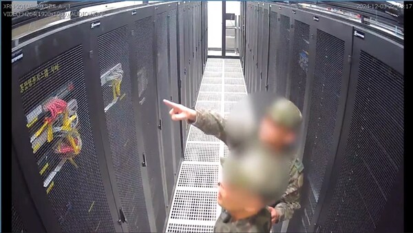 12.3 계엄 당시 선관위 서버실에 침입해 특정 서버들을 찾고 있는 대령 계급의 계엄군 요원. 팔의 부대마크는 가려져 있었지만 착용한 전투모에 반짝이는 대령 계급장이 달려 있는 것을 확인할 수 있었다. (국회 행정안전위원회 제공.)