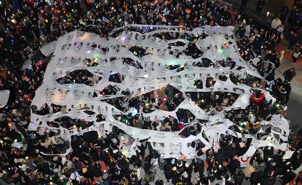 12일 오후 서울 영등포구 국민의힘 당 사무실 앞에서 열린 윤석열 대통령 탄핵 촉구 촛불 집회 행진에 참석한 시민들이 윤 대통령의 탄핵소추안 투표에 불참한 국민의힘 의원들을 규탄하는 현수막을 찢고 있다. 2024.12.12 연합뉴스