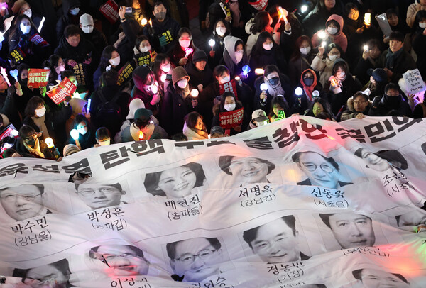 12일 오후 서울 영등포구 국민의힘 당 사무실 앞에서 열린 윤석열 대통령 탄핵 촉구 촛불 집회 행진에 참석한 시민들이 윤 대통령의 탄핵소추안 투표에 불참한 국민의힘 의원들을 규탄하는 현수막을 들어올리고 있다. 2024.12.12. 연합뉴스