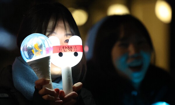 윤석열 대통령 탄핵소추안이 가결된 14일 서울 여의도 국회 앞에서 열린 촛불집회에서 한 참가자가 탄핵 문구가 적힌 응원봉을 들고 있다. 연합뉴스