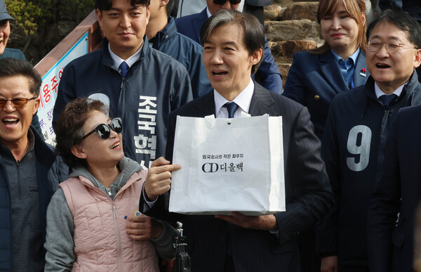 경남 거제시 김영삼 전 대통령 생가를 찾은 조국혁신당 조국 대표가 한 지지자로부터 '외국회사의 작은 파우치 CD 디올백'이라고 적인 가방을 받은 뒤 웃고 있다. 2024.3.31. 연합뉴스