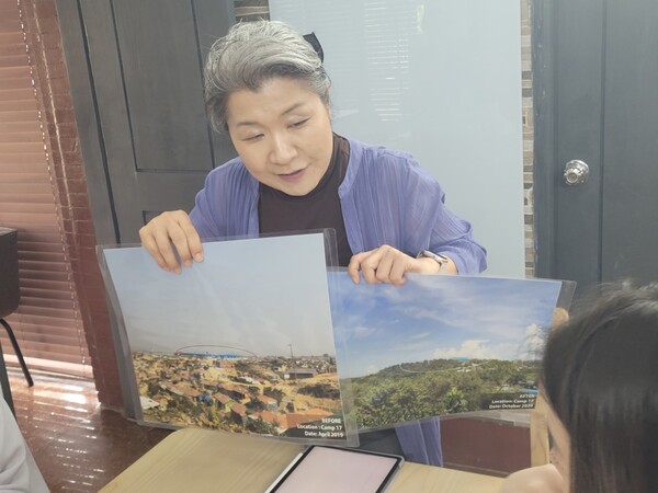 요코 아카스카 캠프 소장이 취사용 가스스토브가 공급되기 전 뒷산의 황량한 풍경과 녹색 숲이 살아난 현재 사진을 비교하며 LPG가스가 땔감을 대체한 뒤 변화를 설명하고 있다. 2024.12.2. 김진호 에디터 