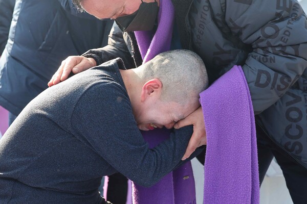 10.29 이태원 참사 유가족이 18일 오후 서울 용산구 대통령실 인근에서 국민의힘이 이날 의결한 이태원 참사 진상규명 특별법에 대한 대통령 거부권 행사 건의를 규탄하며 삭발한 뒤 가족의 품에 안겨 흐느끼고 있다. 2024.1.18. 연합뉴스