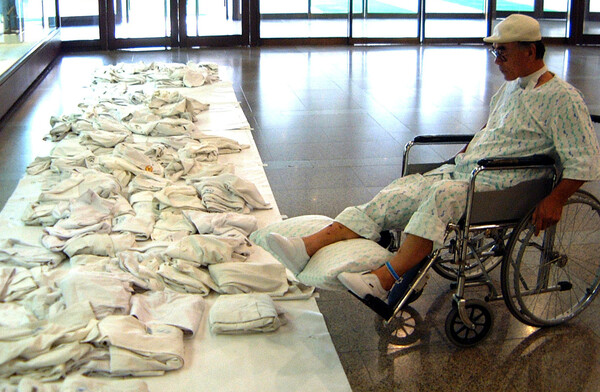 경기도 수원시 아주대학교병원 로비에서 의사들이 파업에 동참하며 벗어놓은 가운을 휠체어에 탄 한 환자가 안타까운 표정으로 바라보고 있다. 2000.8.11.  