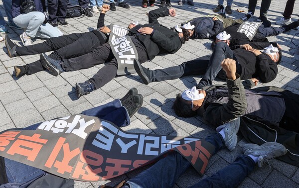 문화민주주의실천연대 등 단체 회원들이 11일 서울 용산구 대통령 집무실 인근에서 열린 '윤석열차' 예술검열 규탄 기자회견에서 가면을 쓰고 눕는 퍼포먼스를 하고 있다. 2022.10.11. 연합뉴스