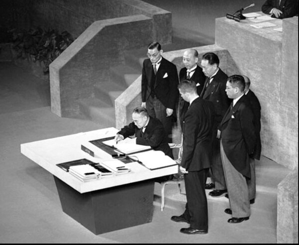 1951년 9월 미국 샌프란시스코에서 체결된 미일 강화조약에 서명하는 요시다 시게루 당시 일본총리(앉은 사람)와 이를 지켜보고 있는 미국 일본 관리들.  위키피디아