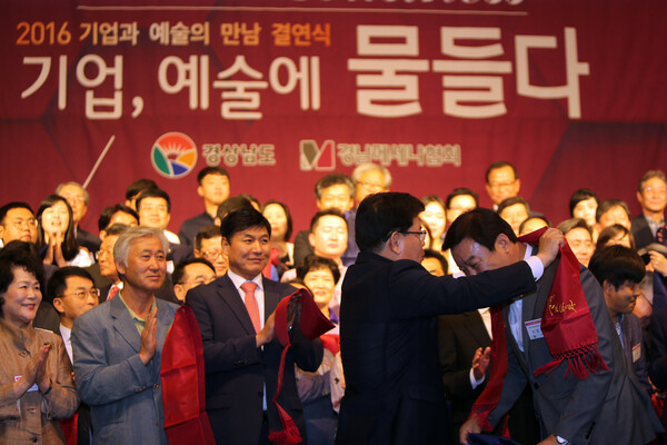 손교덕 경남메세나협회장이 창원 리베라컨벤션에서 열린 '2016 기업과 예술의 만남 결연식'에서 문화단체 대표에게 결연을 상징하는 목도리를 둘러주고 있다. 2016.9.21. 연합뉴스 