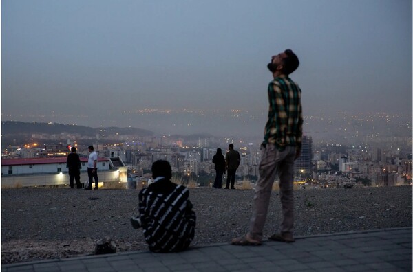 13일 이스라엘군의 대규모 공습 중에 굉음과 함께 연기가 피어오른 이란 수도 테헤란의 언덕 위에 시민들이 모여 하늘을 올려다 보고 있다.  뉴욕타임스  6월 13일 