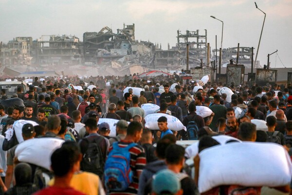 6월 17일, 이스라엘과 하마스 간 전쟁이 계속되는 가운데, 인도적 지원 트럭들이 이스라엘이 통제하는 지킴 국경 검문소를 통해 가자지구 북부로 진입한 후, 밀가루 자루를 든 사람들이 자발리아 서부 알라시드 거리를 걷고 있다. 2025.6.17.AFP 연합뉴스