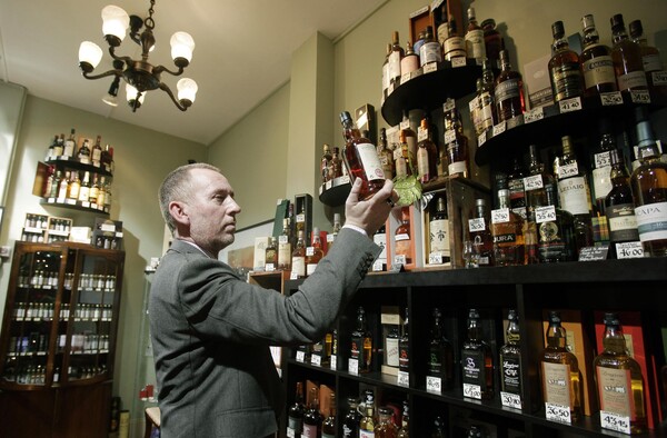 영국 런던의 한 주류전문점에서 한 위스키 전문가가 스카치 위스키 병을 들여다보고 있다. 영국은 중국 정부와 앞으로 스코틀랜드에서 생산된 위스키에만 '스카치 위스키'라는 상표를 붙이기로 협약을 맺었다. (EPA=연합뉴스)