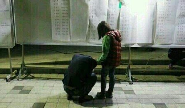 지난 2014년 4월16일 세월호 참사 당일 진도 체육관 앞에서 임경빈 군의 아버지가 생존자 명단을 보고 주저앉아 울고 있다. 그 옆에 서있는 아이는 경빈 군의 여동생.  전인숙 씨 사진 제공.   