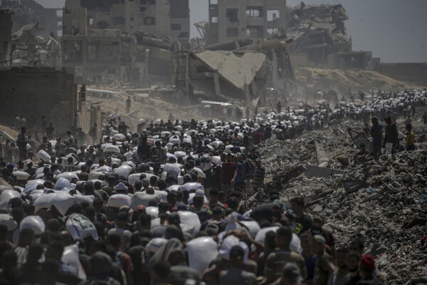 27일 가자 북부 지킴 지역의 식량 배급지 인근에서 팔레스타인 난민들이 밀가루 자루를 메고 가고 있다. 2025. 07. 27 [EPA=연합뉴스]