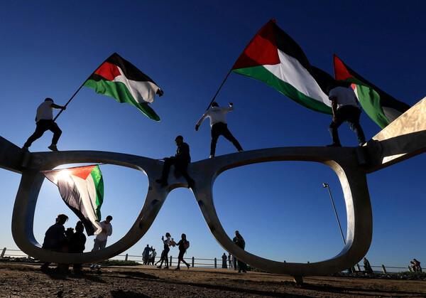 남아프리카공화국 케이프타운의 씨 포인트 산책로에서 27일  팔레스타인 지지 운동가들이 가자의 아사 위기에 항의하면서 팔레스타인 깃발을 흔들고 있다. 2025. 07. 27 [로이터=연합뉴스]