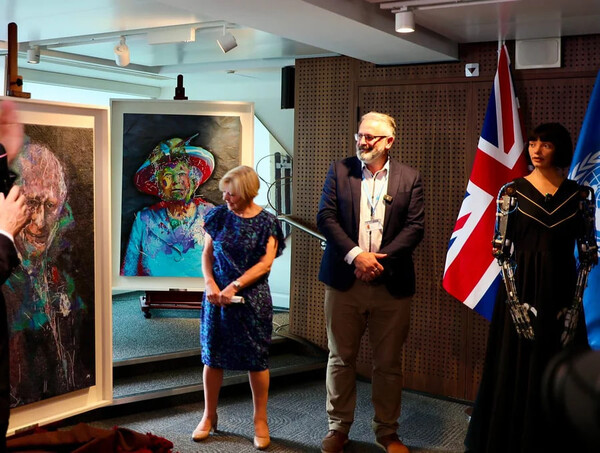 오른쪽에 서 있는 영국 AI  로봇 아이다(Ai-Da)/맨 오른쪽)가 그린 영국 찰스 3세 국왕의 초상화 등 그림이 공개되면서 영국 미술가협회는 인간과 AI의 창의성에 대한 윤리적 질문에 직면했다. (flickr)