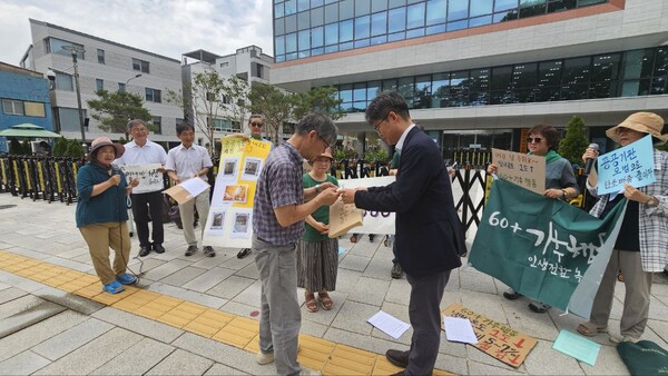 기자회견장에 나온 국정기획원 직원에게 정책제안서아 보고서 등을 전달하는 60+기후행동 박태주, 이정희 공동대표.