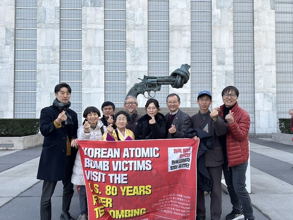 존 레논 암살에 사용된 리볼버를 쓸 수 없게 묶어 형상화한 청동상 '묶여 있는 총' 앞에서.