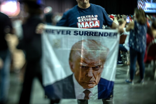 도널드 트럼프 전 미국 대통령이 11일(현지시간) 플로리다주 팜비치에 있는 '클럽 47'에서 유세하는 가운데, 한 지지자가 트럼프의 얼굴 사진과 '절대로 굴복하지 않아'라는 글귀가 새겨진 플래카드를 펼쳐 보이고 있다. 가슴의 MAGA는 '미국을 다시 위대하게 만들자'는 구호. 클럽 47은 트럼프가 내년 11월 5일 치러질 대선 유세를 위해 만든 회사다. 2023.10.12. EPA 연합뉴스