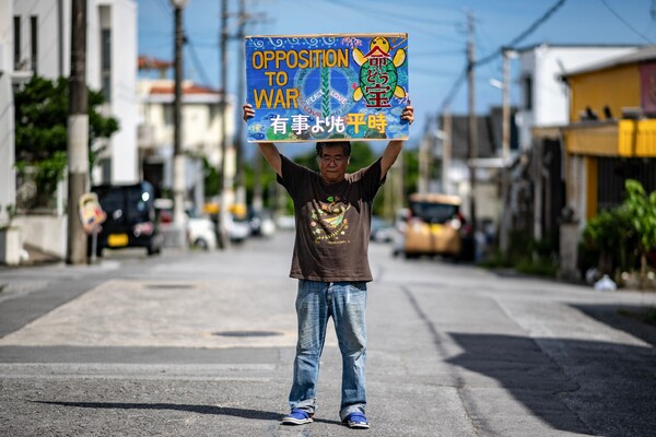 지난 6월 8일 촬영 사진. 1974년 미 해병대원에게 어머니를 잃은 고등학생이었던 긴조 타케마사가 오키나와현 나고시 헤노코 지역에 있는 자신의 집 밖에서 "전쟁 반대"라 쓴 플래카드를 들고 있는 모습. 냉전 시대, 오키나와 주둔 미군은 공산주의 확산을 막는 억제력으로 여겨졌다. 이제 도쿄와 워싱턴은 중국의 영토 확장 야망에 맞서 오키나와의 전략적 중요성을 강조한다. 그러나 주민들은 수년 동안 미군과 기지 인원이 연루된 일련의 범죄와 사고에 대해 분노를 표출해 왔다. 2025.6.8. AFP 연합뉴스