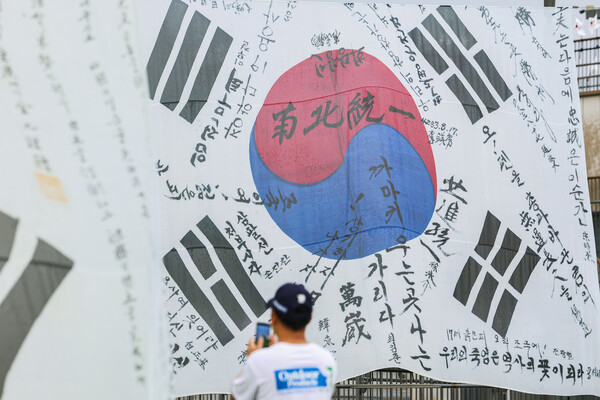 광복 80주년인 15일 서울 용산구 노들섬에서 한 시민이 대형 태극기 앞에서 사진을 찍고 있다. 2025.8.15. 연합뉴스