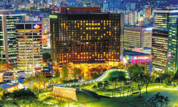 남산을 껴안는 듯한 형태의 힐튼호텔 야경. 그 앞으로 한양도성 성곽이 이어져 있다. (밀레니엄힐튼 서울 제공) 