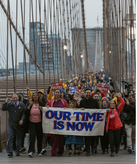 선거전 당시 더불어 사는 세상을 만들 기회가 이제 우리에게 왔다는 메시지를 들고 브루클린 다리를 건너는 맘다니와 다양한 인종과 계층의 지지자들. (Instagram, zohrankmamdani)