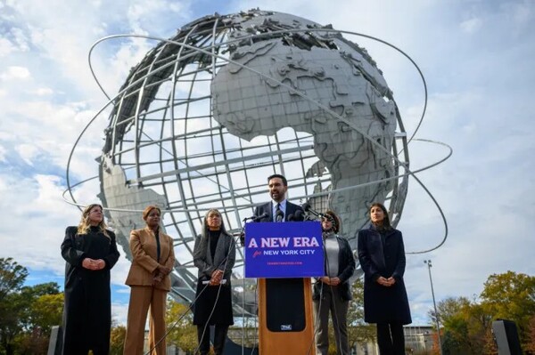 미국 뉴욕 퀸스 플러싱 메도스 코로나파크의 대형 지구본 조형물인 유니스피어 앞에서 조란 맘다니 뉴욕시장 당선인(가운데)이 인수위원회 주요 간부들과 함께 기자회견을 하고 있다. (AFP/연합뉴스)