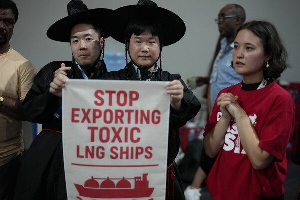 11월 17일, 브라질 벨렘에서 열린 제30차 유엔 기후변화협약(COP30) 정상회의 기간 중 'Don't Gas Asia' 시위에서 한국의 전통 모자 갓을 쓴 활동가들이 "독성 LNG 선박 수출 중단"이라고 쓰인 팻말을 들고 있다. 2025.11.17. AP 연합뉴스